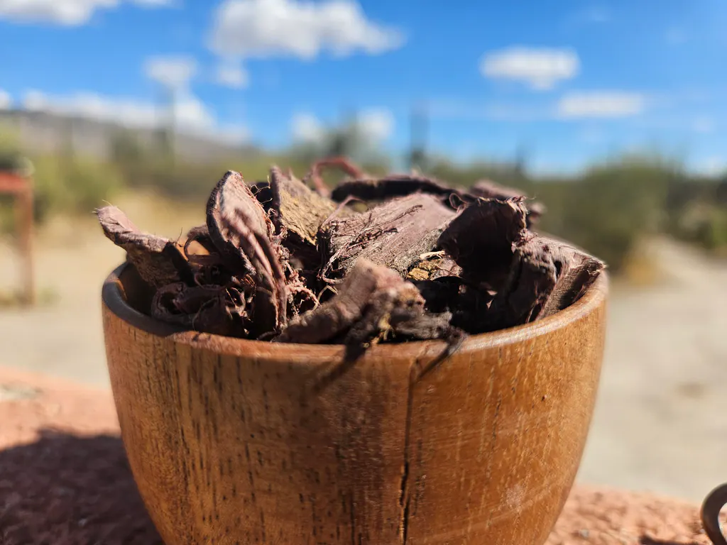 Close view of irregular Mimosa hostilis root bark chips showing their layered, fibrous grain.