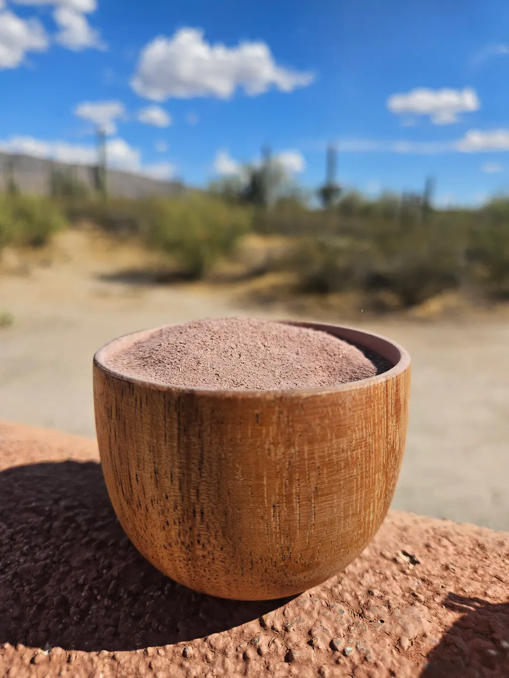 A full wooden bowl of fine Mimosa hostilis root bark powder outdoors.