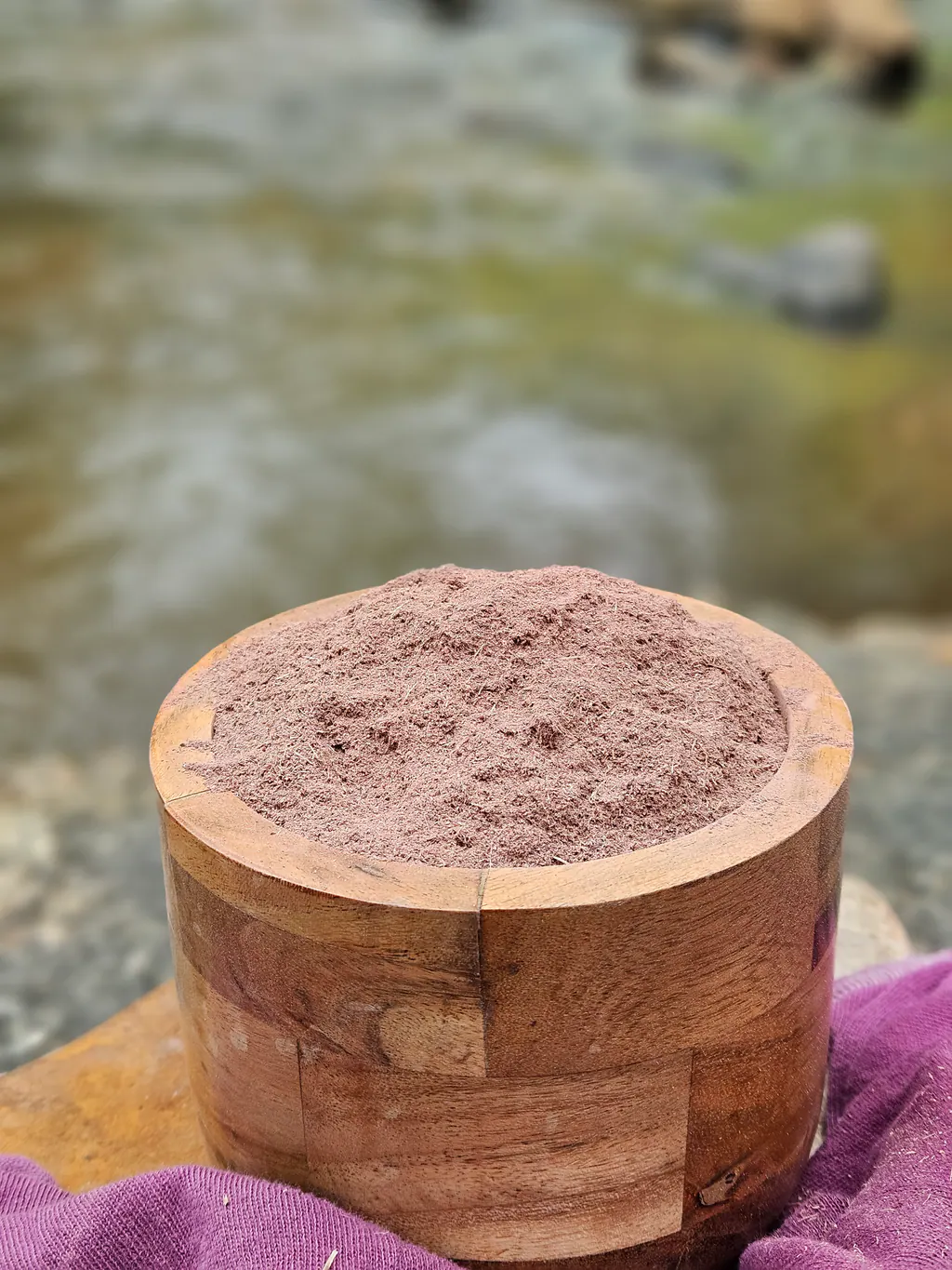Fine Mimosa hostilis root bark powder in a wooden bowl beside a creek.