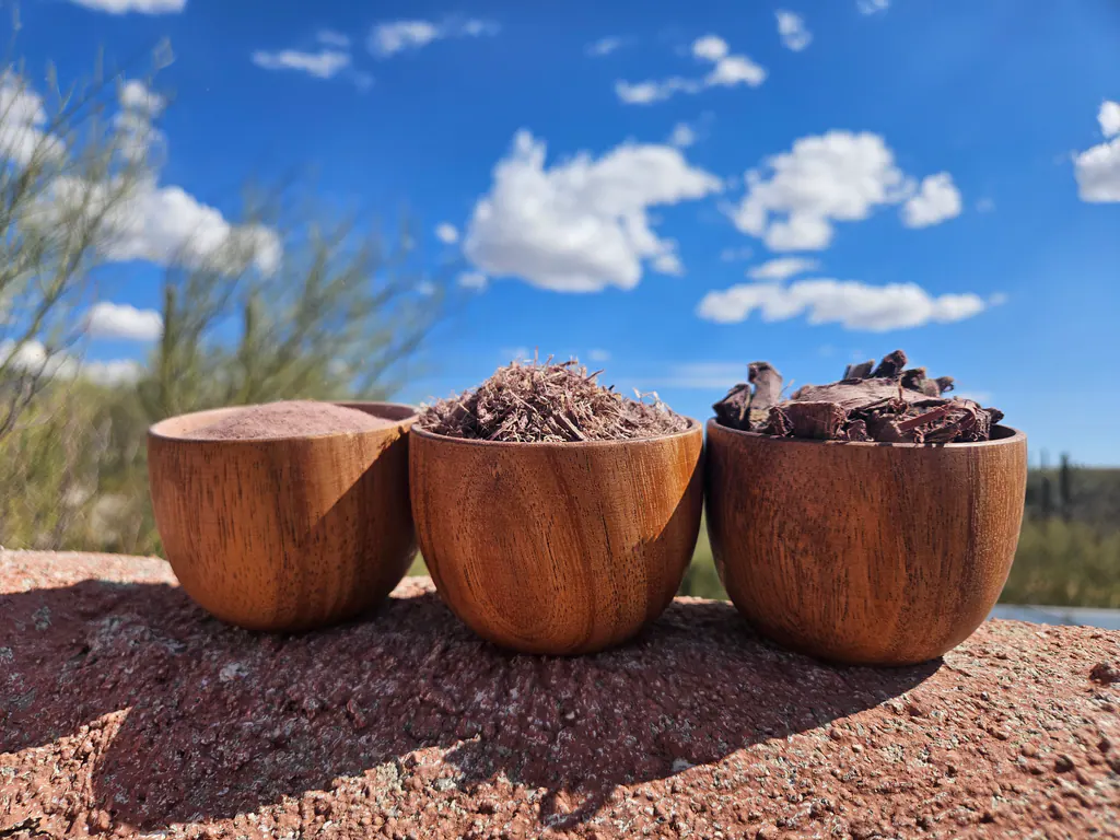 Three bowls of Mimosa hostilis root bark forms against blue sky and clouds.