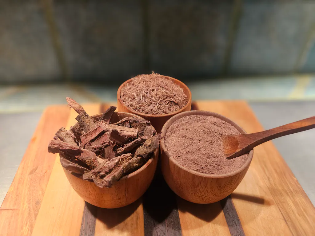 Three wooden bowls holding Mimosa hostilis root bark powder, shredded bark, and chips, with a wooden spoon.